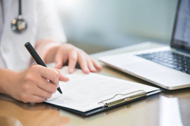 kadın doktor dizüstü bilgisayar kullanma ve bir şey panosuna yazma