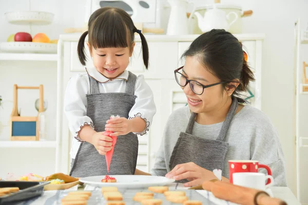 Asiático Kid e jovem mãe decorar biscoitos . — Fotografia de Stock