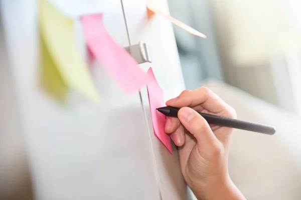 Vrouwelijke hand schrijven op post-it notities. — Stockfoto