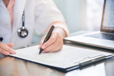 kadın doktor dizüstü bilgisayar kullanma ve bir şey panosuna yazma