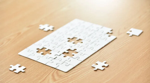 White jigsaw puzzle on wooden desk.