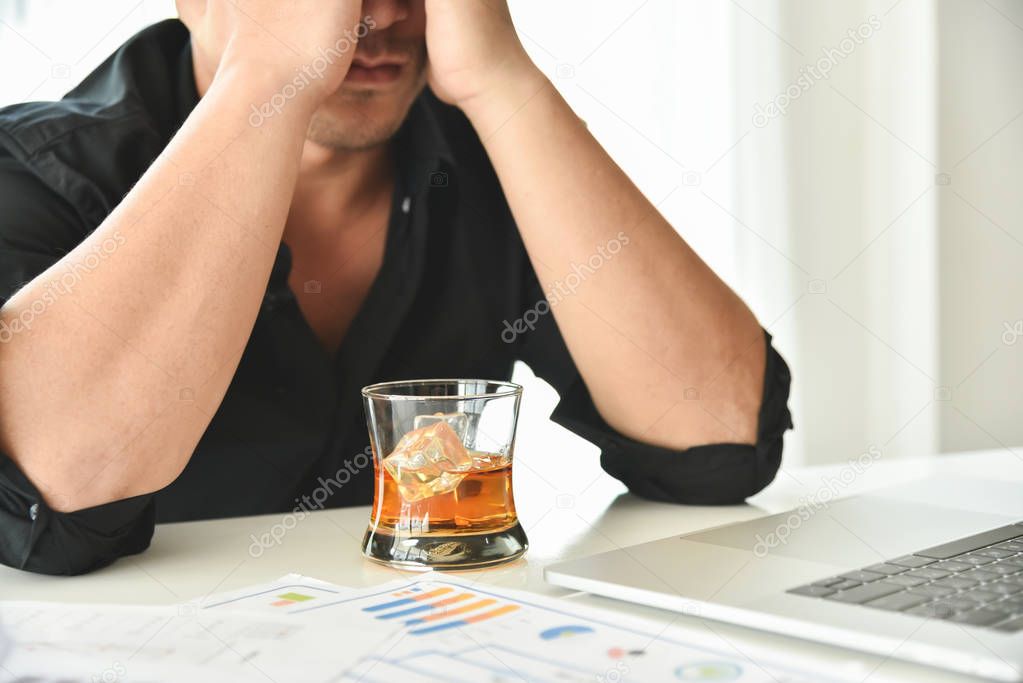 Alcohol addicted businessman is holding whiskey glass.