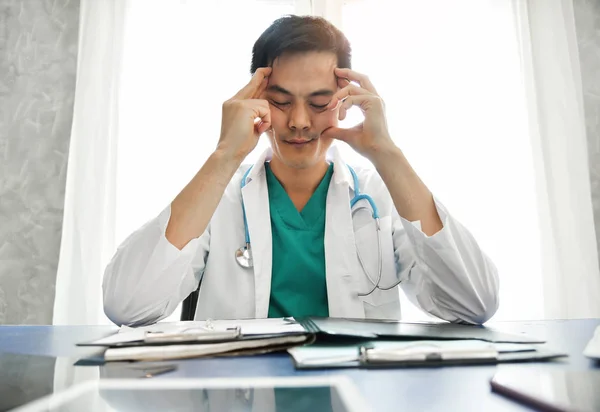 Estressado Jovem Asiático médico masculino está trabalhando . — Fotografia de Stock