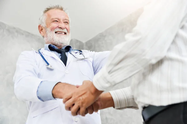 Senior doctor masculino es apretón de manos a asiático paciente masculino . — Foto de Stock