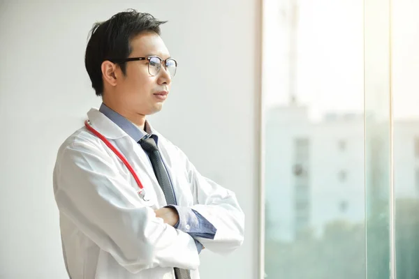 Ritratto di giovane asiatico maschio medico sta posando con le braccia incrociate . — Foto Stock