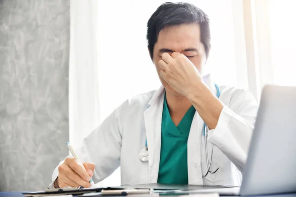 Estressado Jovem Asiático médico masculino está trabalhando . — Fotografia de Stock