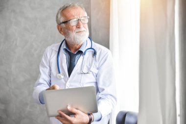 Kıdemli erkek doktor dizüstü bilgisayar kullanan.