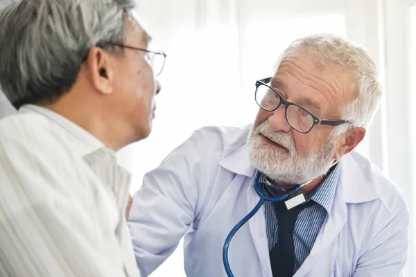 Старші чоловіки лікар говорить з азіатських пацієнта чоловічої статі. — стокове фото