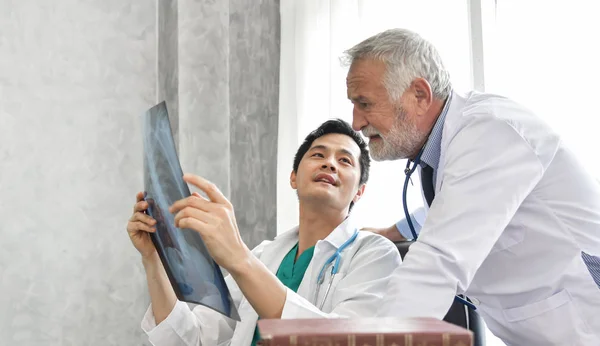 Senior masculino y joven asiático los médicos están examinando radiografía — Foto de Stock