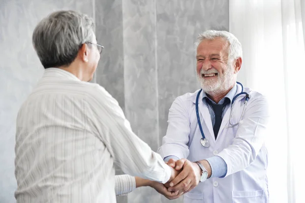 Senior male Doctor is handshaking to Asian male patient.