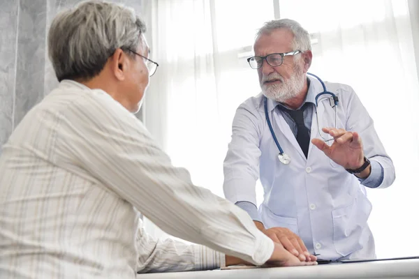 Médico do sexo masculino sênior está discutindo com paciente masculino asiático . — Fotografia de Stock