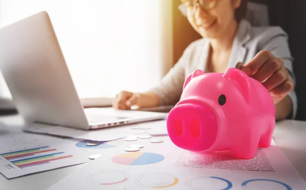 Mujer poniendo monedas en Pink Piggy Bank — Foto de Stock