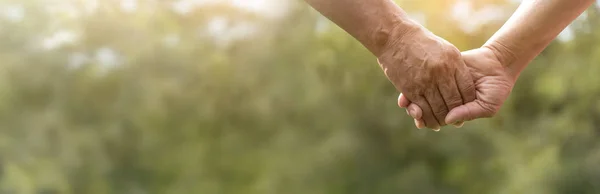 Kıdemli çift yeşil doğa konusunda el ele tutuşuyor.