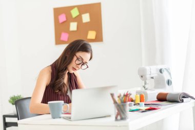 Genç kadın moda tasarımcısı işyerinde çalışıyor..