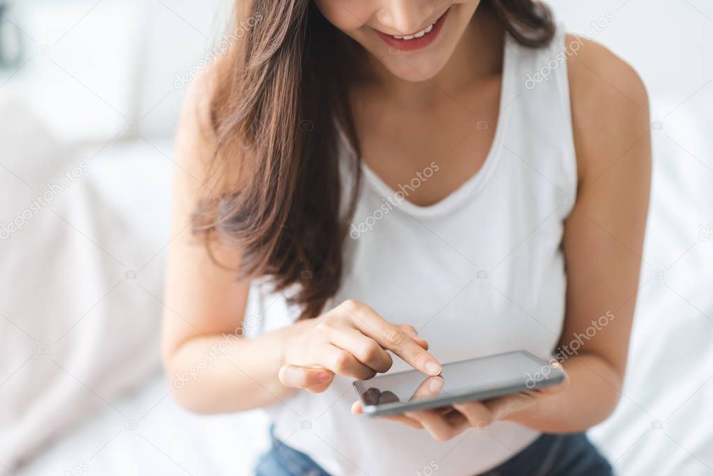 Smiling Asian woman using digital tablet computer while relaxing