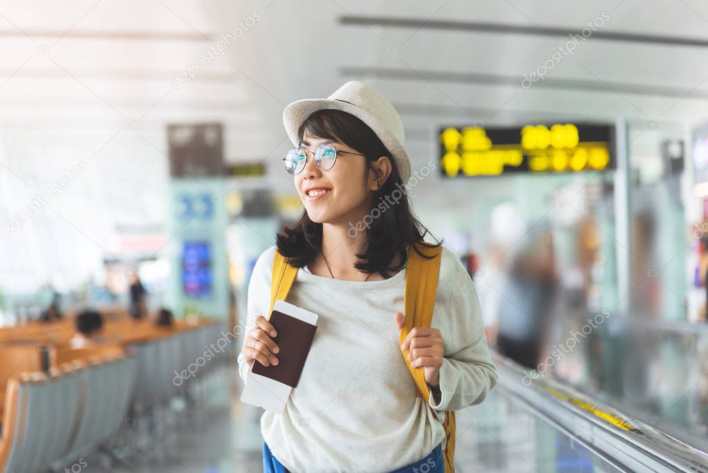 Asian woman wear glasses, hat with yellow backpack is holding fl