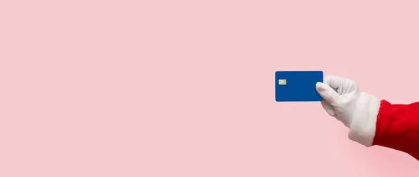 Santa Claus mano sosteniendo tarjeta de crédito de plástico sobre rosa aislado —  Fotos de Stock