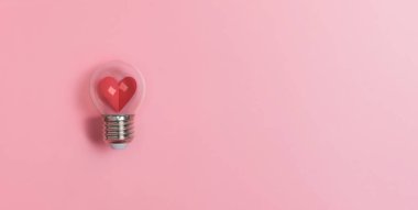 Kırmızı kalp pembe arkaplanda ampulde fotokopi alanı ile. 