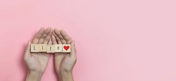 Hands holding Wood cubes with Life text and red heart. — Foto de Stock