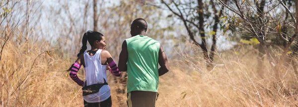 Happy African couple jogging in a autumn forest.