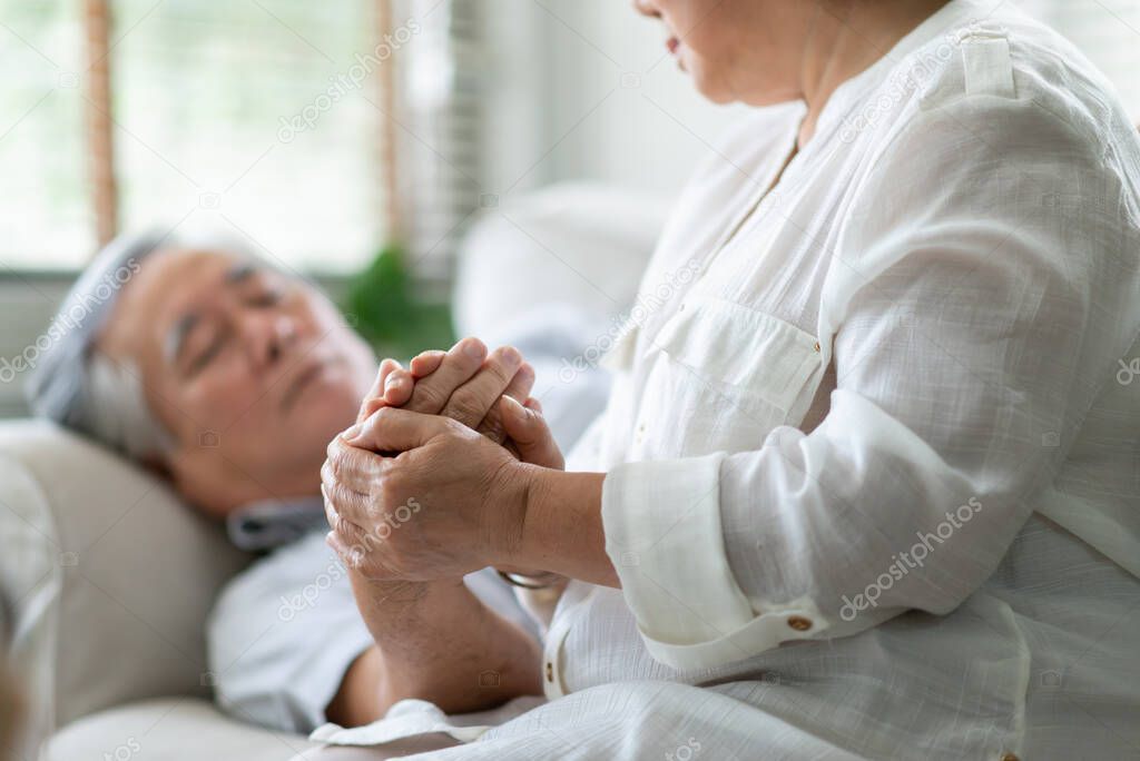 Asian Old Woman holding hand Senior man while him having a fever. Elderly couple comforting together. Symptom, illness, disease.