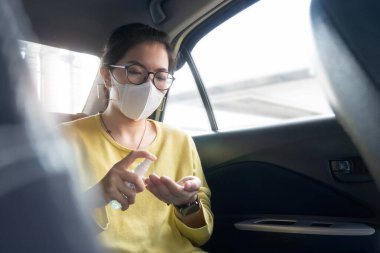 Yeşil ya da sarı tişörtlü Asyalı kadın yolcu ve koruyucu maskeyle avuçlarına ve ellerine dezenfektan alkol sıkarak Coronavirus ya da Coronavirus 'u arabada önlüyor. Temizlik, Antiseptik, Hijyen, Sağlıklı ve Sağlık Konsepti.