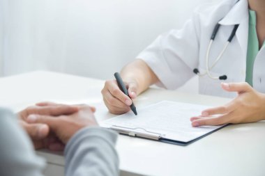Asyalı Kadın Doktor, yaşlı bir adamla hastanedeki beyaz tıp odasındaki semptomları hakkında tartışıyor ve ona danışıyor. Hastalık, hastalık, grip, Covid-19, Coronavirüs, Salgın.