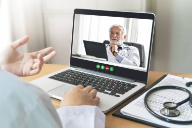 Kıdemli Doktor ve hekim ekibi video görüşmesi yapıyor, internet üzerinden salgın virüse danışmanlık yapıyorlar, laptoplu kablosuz teknoloji ile tıbbi odada buluşuyorlar. Arka görünüm