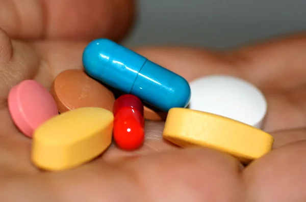 Разноцветные таблетки и капсулы в ладони — стоковое фото