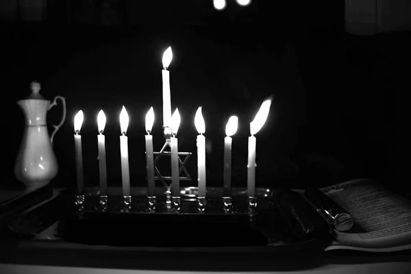 Quemando Janucá. El Chanukiah encendido. Fiesta judía Hanukkah. Foto en blanco y negro. Jarra de porcelana con aceite . —  Fotos de Stock
