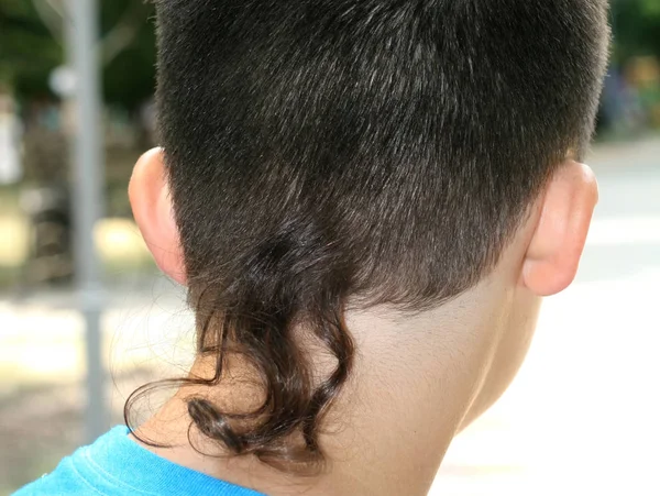 从一缕长发后面看男孩的发型. — 图库照片