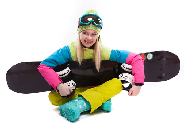 Красива жінка в лижному костюмі сидить зі сноубордом схрещеними ногами — стокове фото