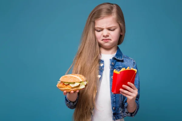 Linda chica sostiene una hamburguesa y patatas fritas —  Fotos de Stock