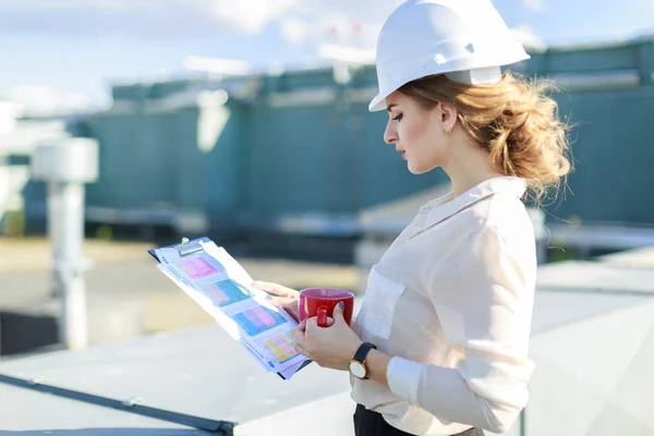 Businesswoman in helmet on the roof with tablet