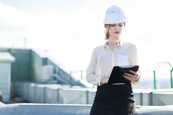 Businesswoman in helmet on the roof with tablet