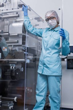 Fabrika içinde tank yakınındaki ayakta bilim adamı