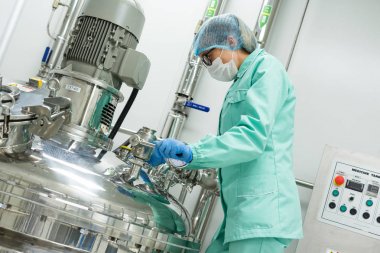 Fabrika içinde tank yakınındaki ayakta bilim adamı