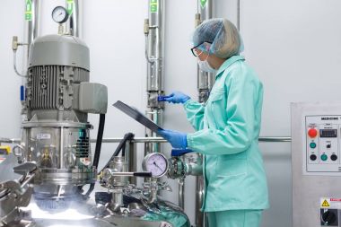 Fabrika içinde tank yakınındaki ayakta bilim adamı