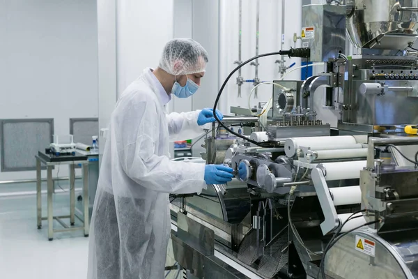Cientista está de pé perto da máquina na fábrica — Fotografia de Stock