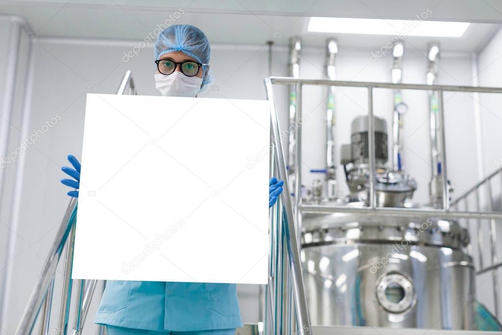 scientist with poster by machine at factory