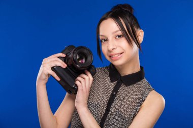 Elinde kamerayla gülümseyen kız