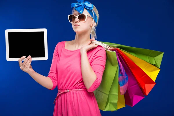 Blond girl with shopping bags and tablet — Stock Photo, Image