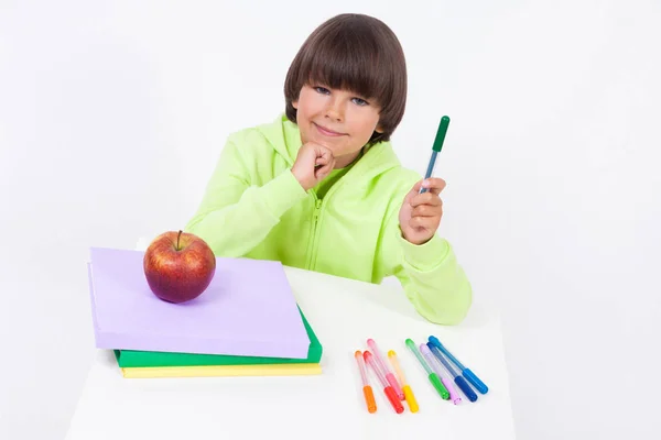 Школьник за столом с книгами и карандашами — стоковое фото