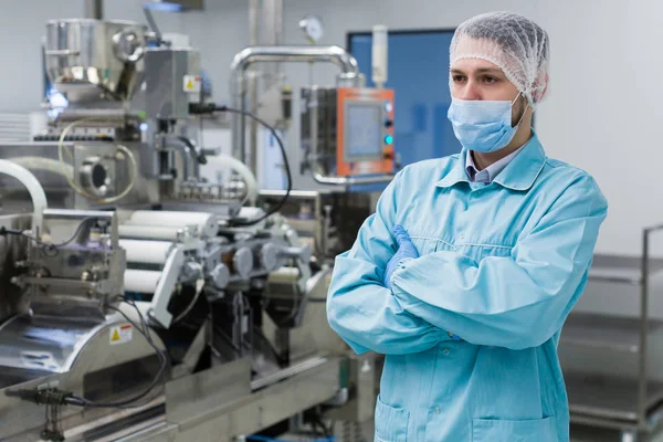 Wetenschapper is permanent in de buurt van machine in fabriek — Stockfoto