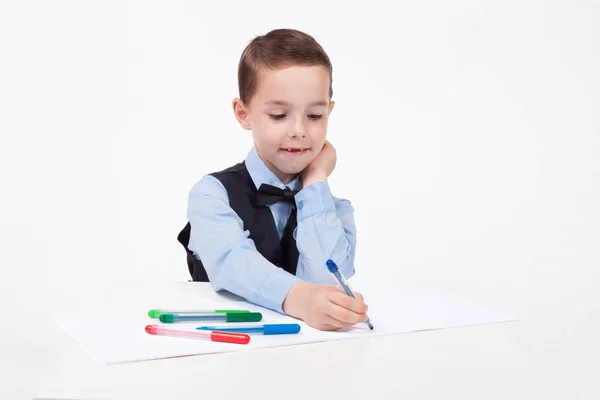 Маленький школьник рисует за столом — стоковое фото
