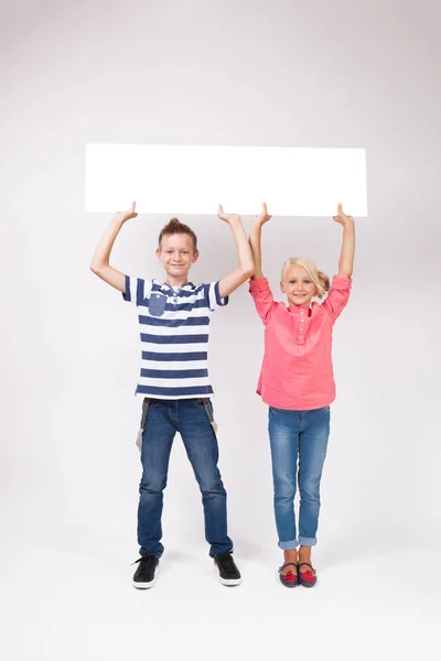 Gelukkig schoolkinderen met witte poster — Stockfoto