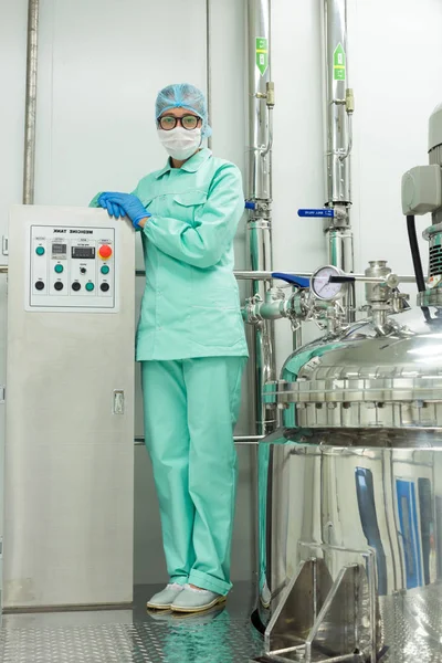 Учёный, стоящий рядом с баком на заводе — стоковое фото