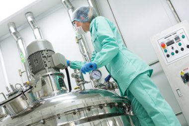 Fabrika içinde tank yakınındaki ayakta bilim adamı