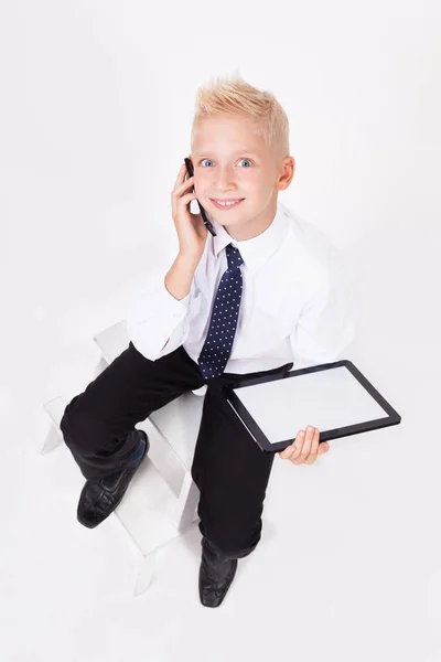 Skolan pojke i skjorta med surfplatta och telefon — Stockfoto