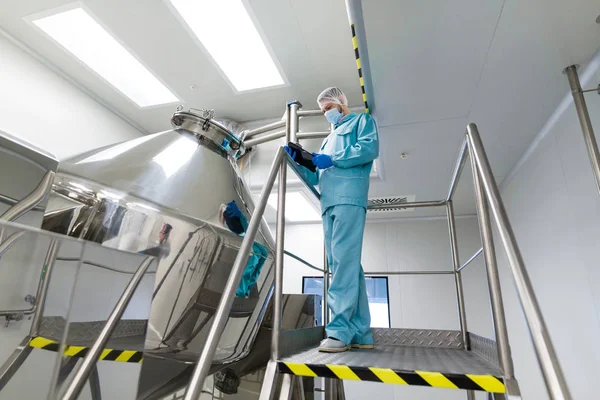 Scientist with tablet by metal tank — Stock Photo, Image